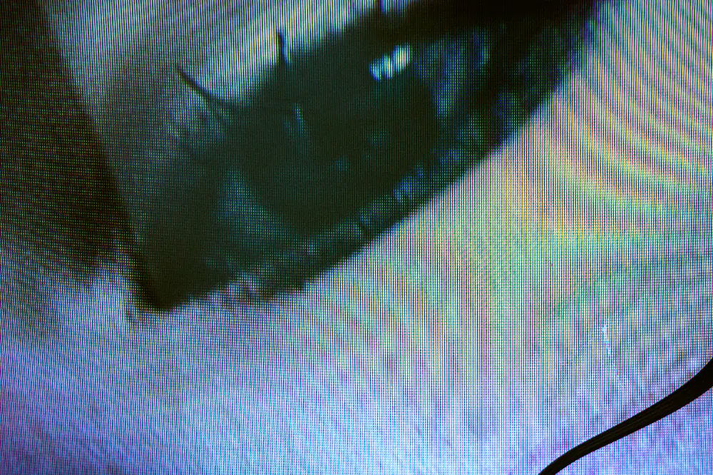 Close-up of an eye seen through iridescent screen lines