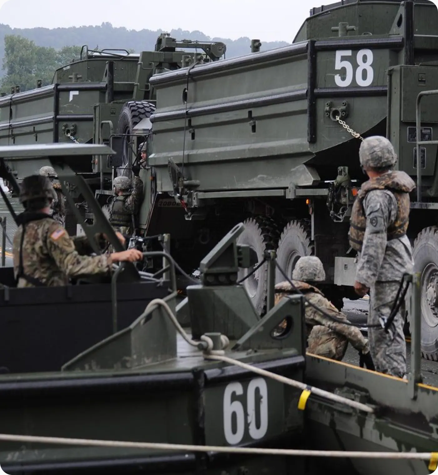 Soldiers working beside military bridging vehicles