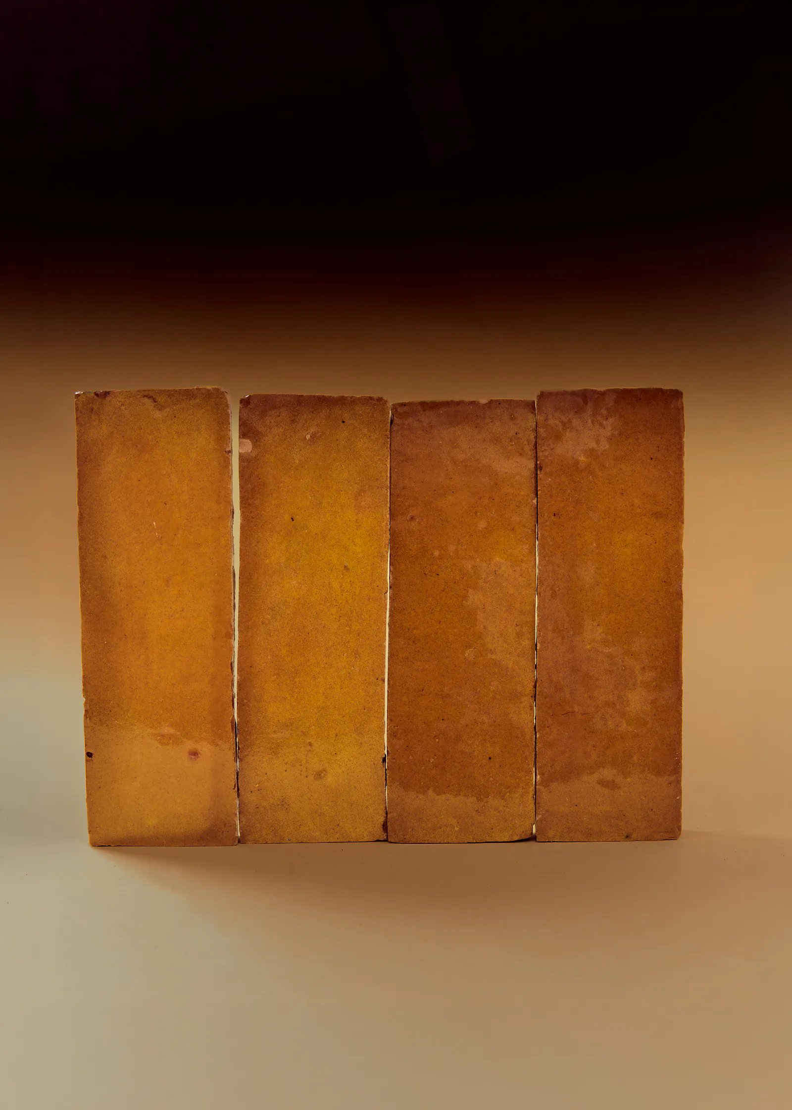Four handmade amber tiles standing in a row