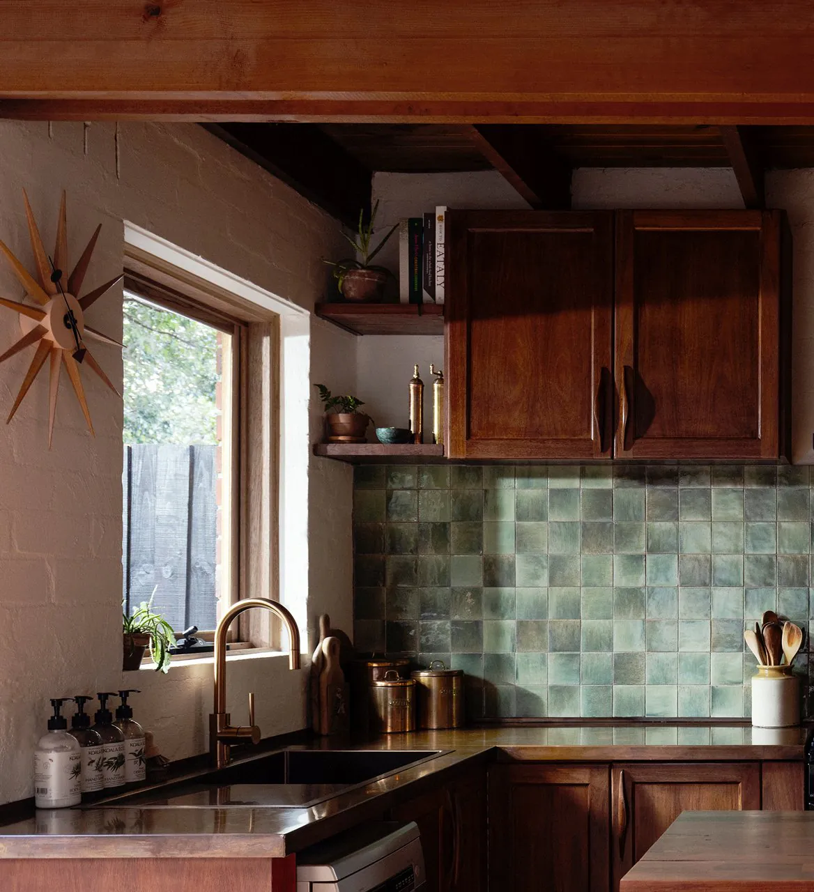 Kitchen with timber cabinets, a green tiled splashback and a sunburst clock