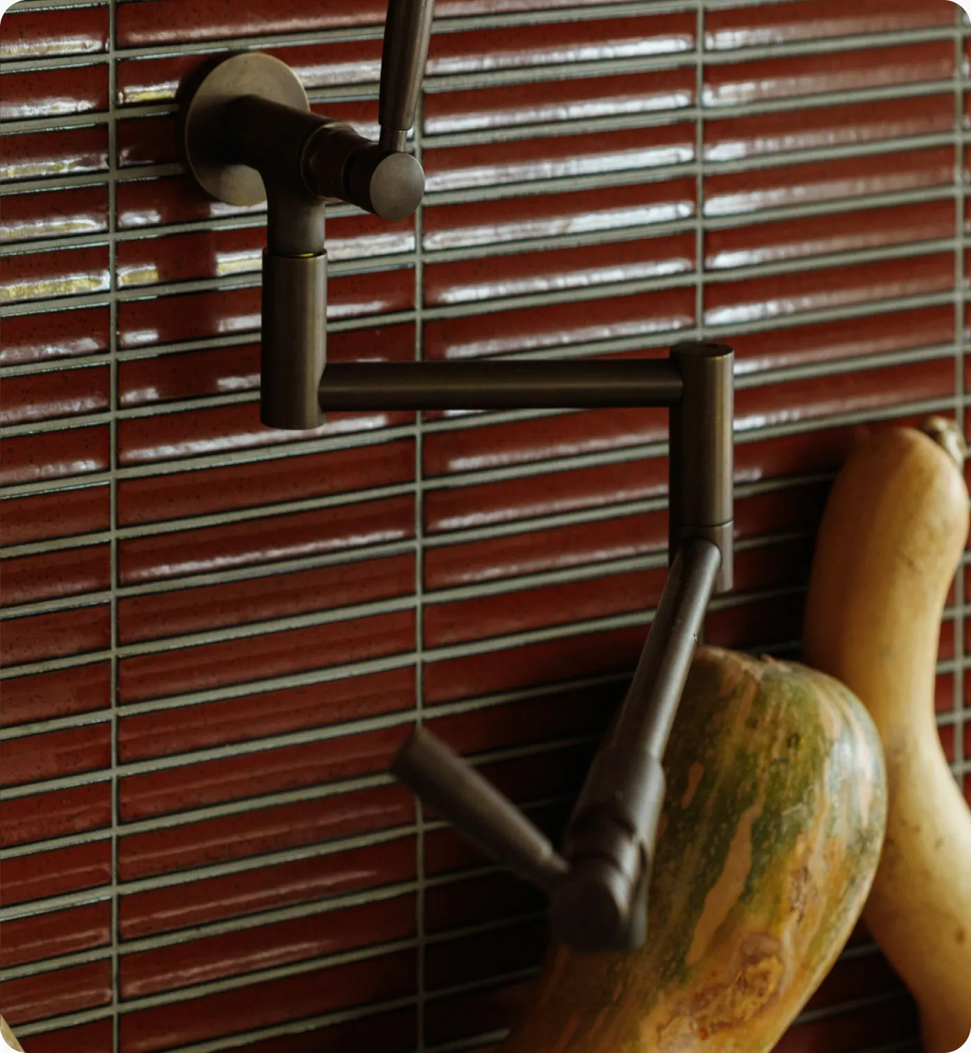 Bronze pot-filler tap against glossy red tiles