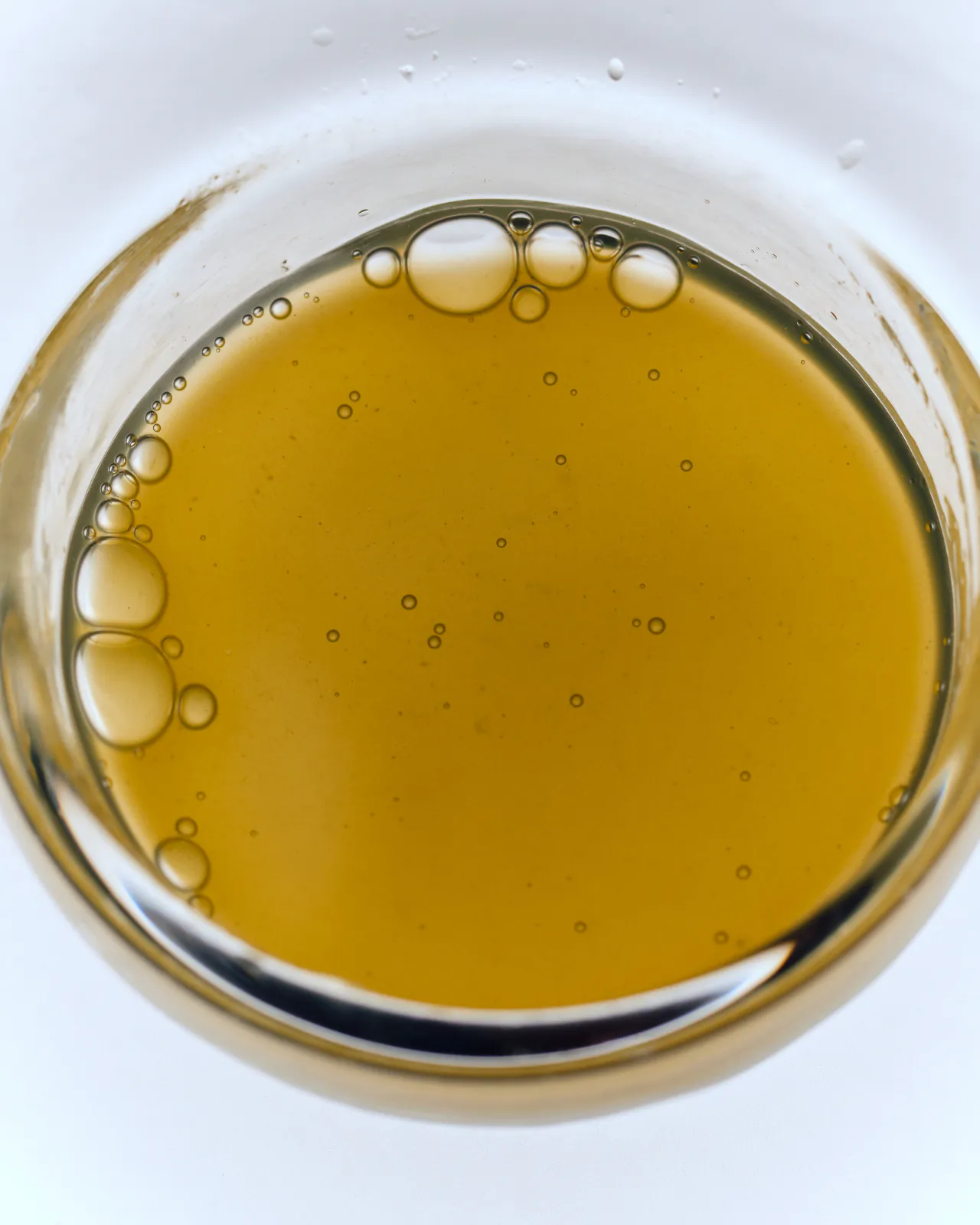 Golden oil droplets in a glass dish, seen from above