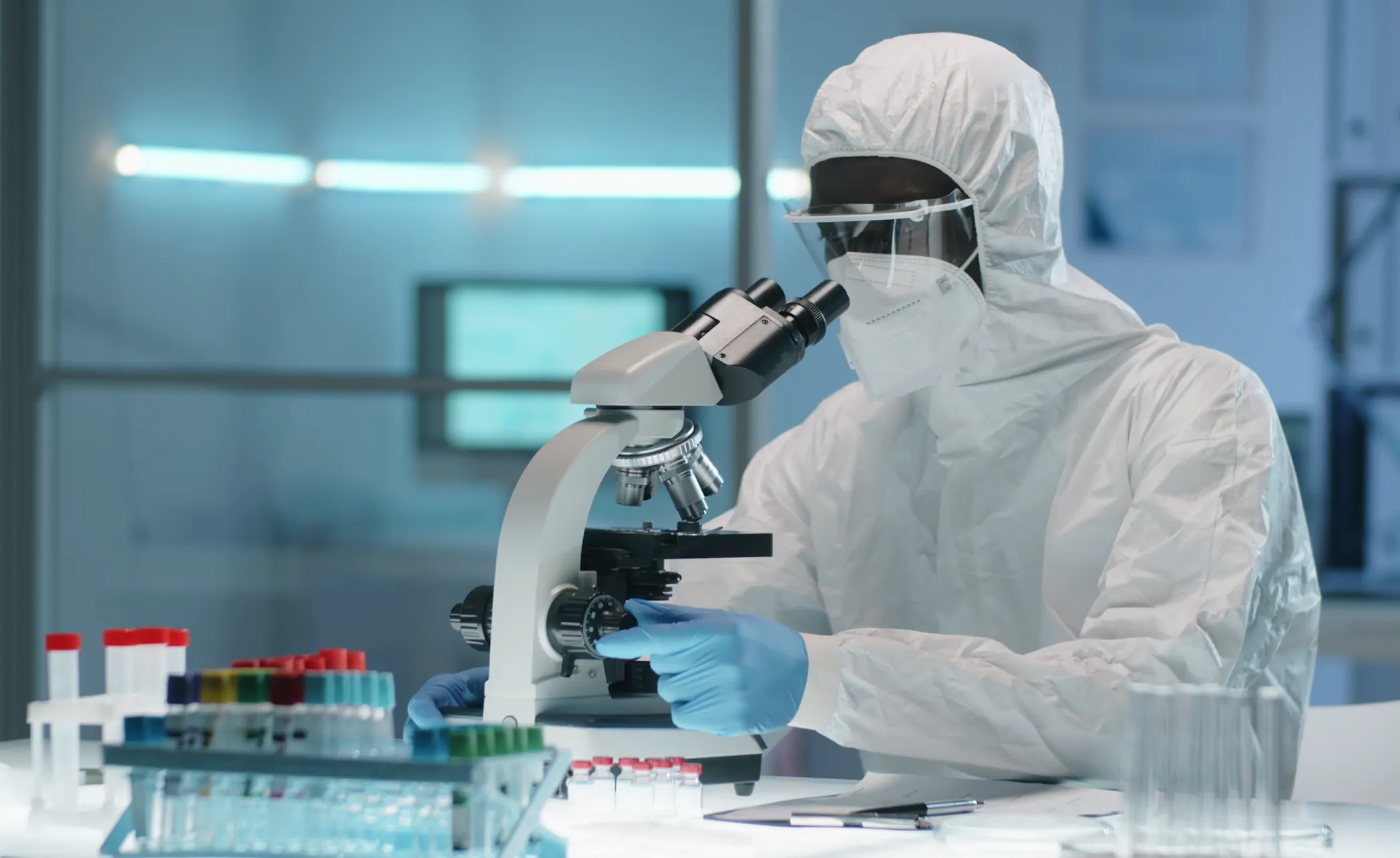Scientist in a cleanroom suit working at a microscope